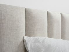 an upholstered headboard with white sheets and pillows