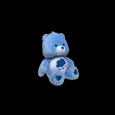 a blue teddy bear sitting up against a black background