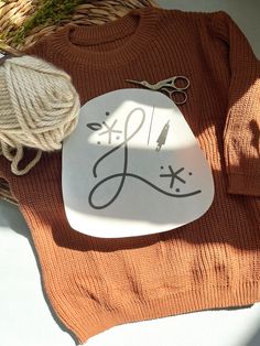 a white plate with the word love written on it next to yarn and knitting needles