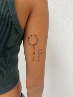 a woman's arm with a small tattoo of a dandelion on it