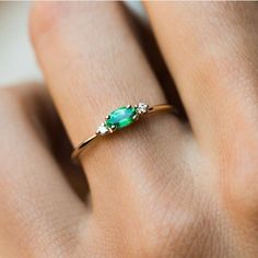 a woman's hand with a green ring on top of her finger and an emerald stone in the middle