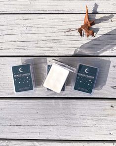 three wax cubes sitting on top of a wooden table next to an autumn leaf