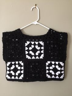 a black and white crocheted sweater hanging on a wall