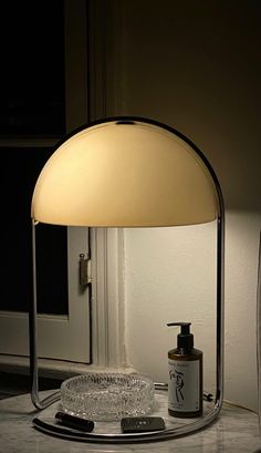 a table lamp sitting on top of a counter next to a bottle and soap dispenser