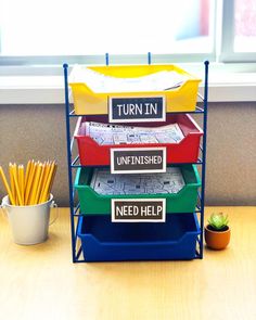 a stack of four trays sitting on top of a table next to a potted plant