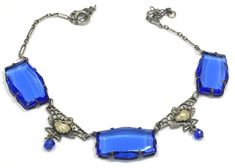 This pretty delicate vintage Czech choker features three open back bevelled Czech royal blue glass alternating with silver plated filigree set with a textured pearlized cabochon (almost has a clam shape) and a small blue glass bead dangle.  The chain has silver plated elongated links and  measures 15" L x approx. .60" W and has a spring ring clasp.  Each blue glass measures 1.2" x .60" .  The necklace is in very good to excellent vintage condition for the age and the glass under magnification lo Vintage Blue Glass Jewelry, Silver Glass Evening Jewelry, Silver Glass Jewelry For Evening, Evening Silver Glass Jewelry, Formal Blue Glass Jewelry, Blue Adjustable Jewelry For Evening, Vintage Blue Cabochon Jewelry, Blue Vintage Cabochon Jewelry, Vintage Blue Necklace For Evening