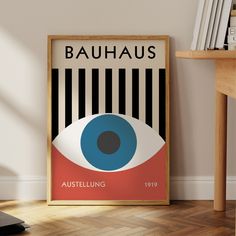 a poster with an eye on it in front of a wooden table and bookshelf