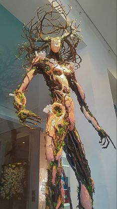 a sculpture made out of branches and twigs in the shape of a woman with her arms outstretched