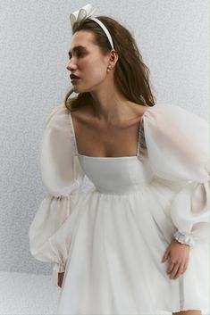 a woman wearing a white dress with puffy sleeves and a bow in her hair