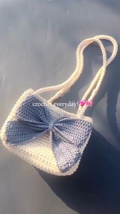 a crocheted purse with a bow on the handle is shown in blue and white