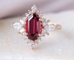 a close up of a ring with a red stone and white diamonds on it's side