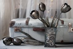 an old suitcase with flowers in it sitting on a table next to a curtained window