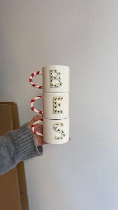 a person holding up three coffee mugs with writing on them