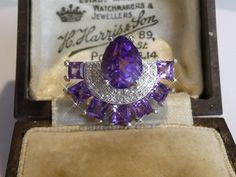 A fine solid silver art deco design fan ring set with real amethysts. set with a large pear shape cut amethyst half surrounded by two rows of cubic zirconias with a border of seven square cut amethysts. measures 1.5cm high x 1.9cm wide, look fab when worn, also have matching earrings please see other listings. Purple Amethyst Art Deco Ring, Art Deco Purple Amethyst Ring For Anniversary, Purple Amethyst Art Deco Ring For Anniversary, Art Deco Purple Amethyst Wedding Ring, Purple Hallmarked Art Deco Amethyst Ring, Art Deco Purple Amethyst Ring, Amethyst Set, Set Ring, Silver Art