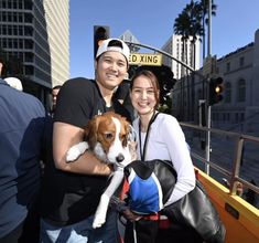 a man and woman pose for a photo with their dog on a boat in the water