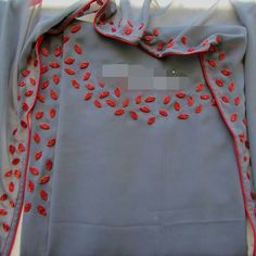 an embroidered shirt with red beads on it