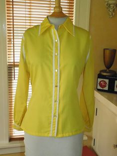 Label:  Judy Bond 1960s Lemon yellow lightweight blouse with white trim - pearlescent buttons and cuffs   Size:  16 /  Bust: 40 /   Overall Length: 26" /  Across Shoulder Seams: 16" /  Sleeves: 24 Condition:  Excellent AMERICAN VINTAGE CLASSICS RWB6139 Spring Formal Yellow Shirt, Spring Yellow Formal Shirt, Yellow Formal Shirt For Spring, Formal Yellow Shirt For Spring, Vintage Yellow Blouse With Buttons, Fitted Yellow Shirt With Buttons, Classic Yellow Blouse With Button Closure, Fitted Yellow Blouse With Button Closure, Fitted Yellow Vintage Blouse