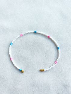 Handcrafted white beaded anklet/bracelet with pink and blue details. Made using small colourful round glass beads and finished with a gold-plated barrel clasp closure. Pair it with our matching Necklace.  * Weight: 3g   * Width: 5mm/2mm  * Made in UK  * Code: 111AWPBS The very best in unique, handmade pieces from BAM-BAM, our anklets and bracelets make great accessories for the beach, festival or club. These small beads have a dainty appearance and can take your best looks from day to night. White Beaded Anklets For Summer, White Bracelet With Letter Beads For Vacation, White Bracelets With Letter Beads For Vacation, White Letter Beads Bracelet For Vacation, White Heishi Beads Strand Necklace, White Round Bead Anklets For Summer, Adjustable White Anklets With Colorful Beads, White Round Beads Anklets For Vacation, White Round Beads Anklet For Summer