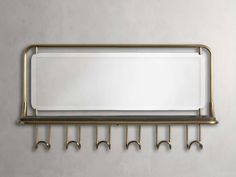 an empty mirror hanging on a metal rack with five hooks in front of it and a white wall behind it