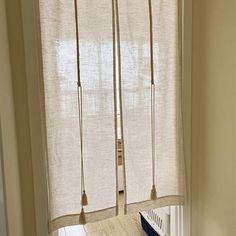 a cat sitting on top of a wooden floor next to a window with white curtains