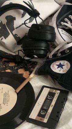 an old record, headphones, and pair of sneakers are laying on a bed