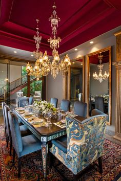 a dining room table with blue chairs and chandelier hanging from it's ceiling