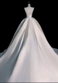 a white wedding dress is on display in front of a black background with the back of it's neckline