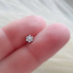 a person's hand holding a tiny diamond ring