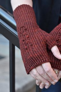 a woman wearing red knitted arm warmers and holding onto a railing with her hand