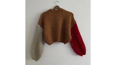 two sweaters hanging on a wall with one red and the other beige, both in different colors