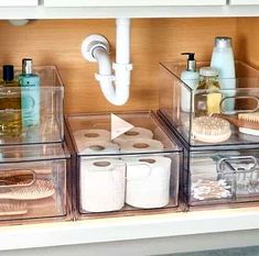 three clear bins with toiletries and other items in them sitting on a counter