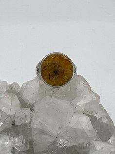 a yellow ring sitting on top of some ice crystals in front of a white background