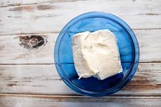 a blue plate topped with white frosting on top of a wooden table next to a knife