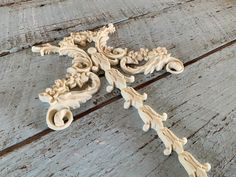 an intricately carved piece of wood sitting on top of a wooden table with peeling paint