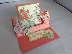 a close up of a greeting card with flowers and butterflies on the front, in an open box