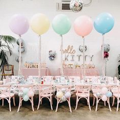 there are many balloons on the tables at this baby's first birthday party with pastel colors