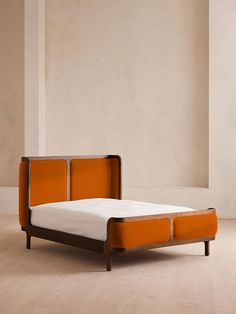 an orange and white bed in a room with wood flooring next to a wall