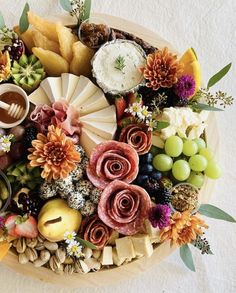 a platter filled with different types of cheeses and fruit on top of a table