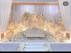 a white wedding cake sitting on top of a table next to a flower covered wall