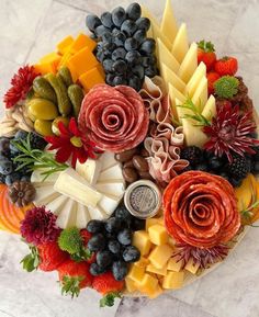 a platter filled with lots of different types of cheeses and fruits on top of each other