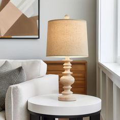 a living room with a white couch and lamp on the table in front of it