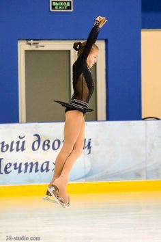 a female figure skating on the ice in a black leotard and short skirt