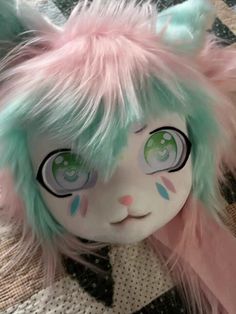 a close up of a stuffed animal with pink and green hair