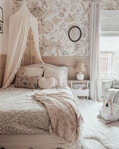 a white bed sitting next to a window in a room with flowers on the wall