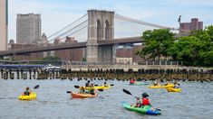 several people are kayaking in the water near a bridge