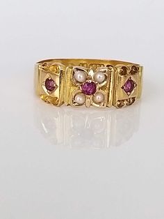 A stunning Edwardian ruby and split pearl 15ct gold ring. Three delightful rubies - Rich red in colour sit with 4 tiny split pearls ... The ornate band measures 6mm wide at the front tapering to 3mm at the back... The gold is a beautiful rich buttery colour. The hallmarks are crisp, Chester 1900 - always a premium... Super ring in excellent condition! This was the year Queen Victoria of the United Kingdom of Great Britain and Ireland died. Her reign of 63 years and 216 days is known as the Victorian era and was the longest of any British monarch until Elizabeth II. It was a period of industrial, political, scientific, and military change within the United Kingdom, and was marked by a great expansion of the British Empire. In 1876, the British Parliament voted to grant her the additional ti Colourful Wedding Ring, Gold Ruby Ring With 17 Jewels For Wedding, Victorian Ruby Gemstone Ring For Wedding, Victorian Yellow Gold Ruby Ring For Wedding, Victorian Red Ruby Ring For Wedding, Victorian Red Ruby Wedding Ring, Victorian Ruby Ring Wedding Birthstone, Victorian Ruby Ring With Birthstone For Wedding, Victorian Style Red Ruby Wedding Ring