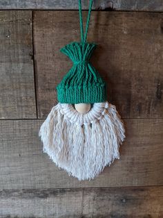 an ornament hanging on the side of a wooden wall with a green knitted hat