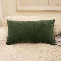 a laptop computer sitting on top of a bed next to a green pillow and blanket