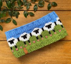 a blue and green knitted purse sitting on top of a wooden table next to a plant