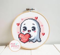 a cross stitch pattern with a cute little ghost holding a heart in it's mouth